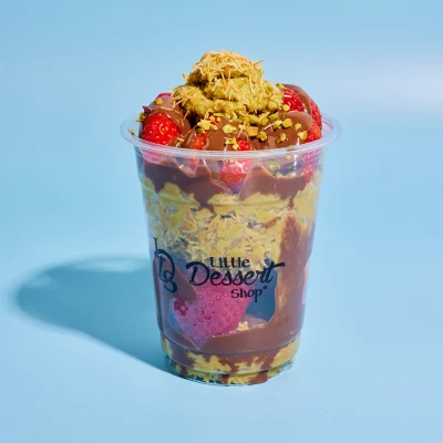 Layered pistachio and strawberry crunch cup with chocolate drizzle